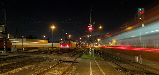 Fototapeta na wymiar bahnsteig mit einem stehenden und einem fahrenden Zug zur blauen stunde