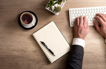 Male hands  in suit typing on white keyboard