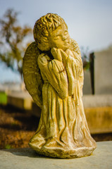 A aged yellow Angel grave statue on a grave. It was white at one time, and the alabaster turned...