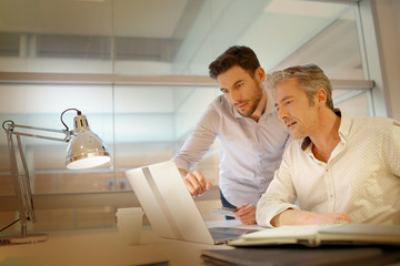 Fototapeta premium Male coworkers talking over ideas in modern office