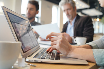 Obraz premium Close up of business woman's hands typing during meeting