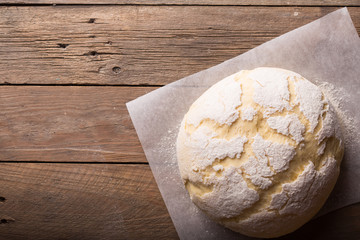 Dough and ingredients for it - eggs flour yeast on brown wooden background. Selective focus.
