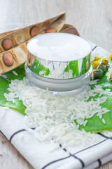 White lotion jar Lotion jars with seeds and flowers around The lotion bottle is placed on the wood.