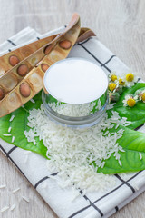 White lotion jar Lotion jars with seeds and flowers around The lotion bottle is placed on the wood.