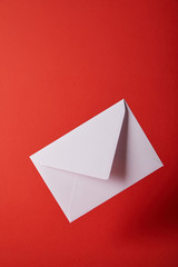 white and empty envelope on bright red background with copy space