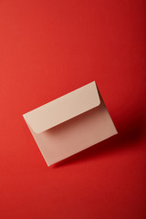 beige, blank and empty envelope on bright colorful red background with copy space