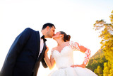 Beautiful wedding couple kissing in the sun near road and trees