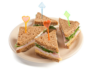 Group of tea sandwiches with  cheese, ham and lettuce on a plate isolated on white background
