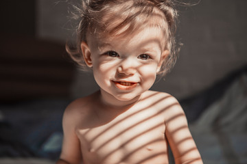 child with tails on his head favors morning in bed in his parents' room on a sunny day. concept of a family of typical, ordinary home-like recreation of a real middle-income family in Europe