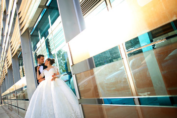 Beautiful bride and groom posing near architecture reflexion