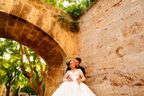 Happy wedding couple posing in park under old arch