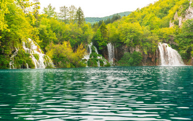 waterfalls flowing in a lake from rivers hidden in the forest, plitvice lakes national park