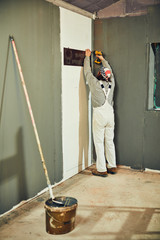 Painter painting walls with a extender roller indoors.