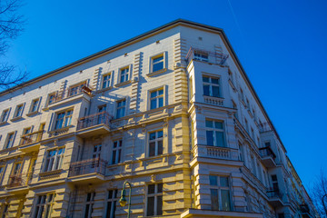 Fototapeta premium yellow corner building with small balcony from the low angle view with deep blue sky