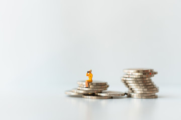 Miniature people, woman sitting on stack coins using as business and financial concept