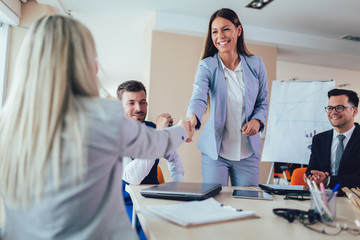 Obraz premium Businesswomen shaking hands in meeting room. Selective focus.