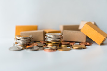 Closeup pile of coins and cardboard boxes using as business and logistics concept