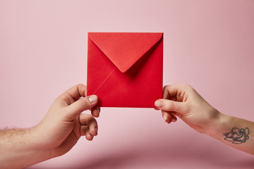 partial view of woman with tattoo and man holding red envelope on pink background