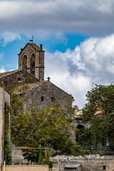 Fototapeta na wymiar Church tower with two brass bells, stone side wall and roof with religious cross, street view of ancient town of Matera, Basilicata, Southern Italy, cloudy summer warm August day
