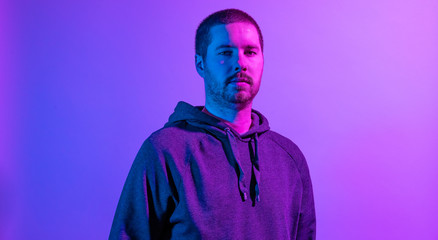 Serious unshaven man posing in purple studio light