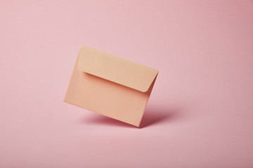 beige and empty envelope on pink background with copy space