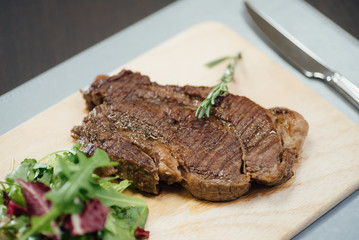 A piece of fried meat and greens on a wooden cutting board on the table
