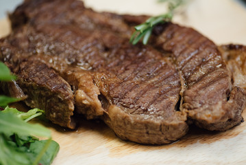 A piece of fried meat and greens on a wooden cutting board on the table