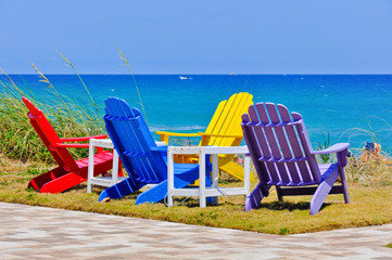 A grouping of colorful Adirondak chairs overlooking the ocean welcomes visitors to a Florida beach