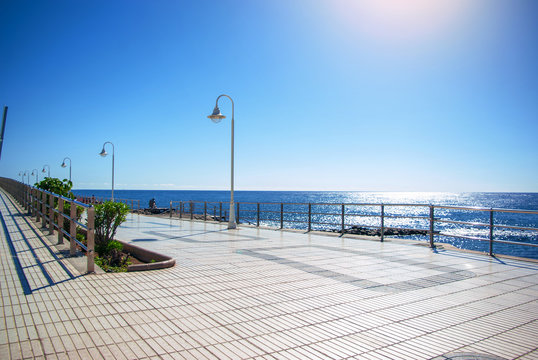Embankment covered with paving slabs with lanterns on the beach