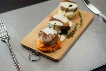 Melted cheese on meat patties on a cutting board on the table