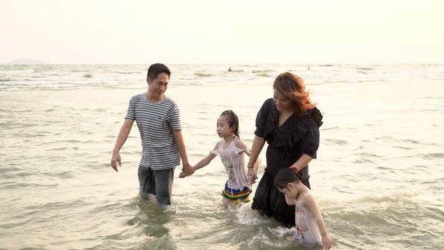 Happy asian family on the beach. Handheld shot.