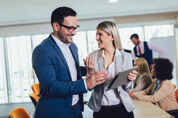 Portrait of two young businesspeople using digital tablet while colleague in background. Selective focus
