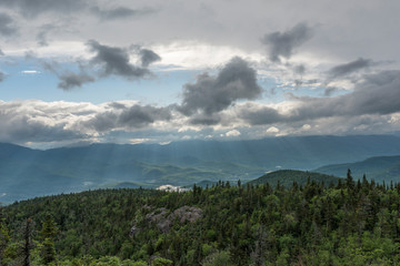 gaps in storm clouds allow sun rays to hit the lush valley floor