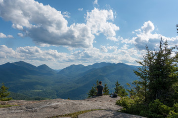 a woman sits upright on a rock enjoying endless mountain views