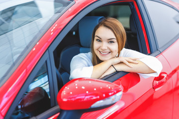 Beautiful happy woman choosing a car at the dealership
