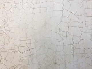 Old dirty shabby white wall with cracked paint texture background.