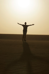 Fototapeta premium man with his arms open in the air, in the desert