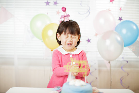 toddler girl making a wish on her third birthday  party at home