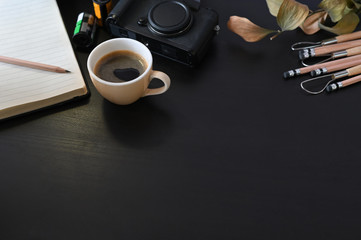 Fototapeta premium Creative workplace camera, coffee and note paper on black table with selective focus.