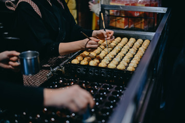 Closeup hand making takoyaki. Takoyaki is a ball Japanese snack popular snack.