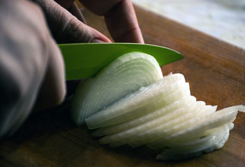 Man cuts onions on the table close up