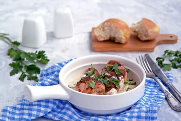 Fried chicken in a creamy garlic sauce or chkmerili chicken in a portioned ceramic pan on a light gray background. Georgian cuisine. Selective focus.