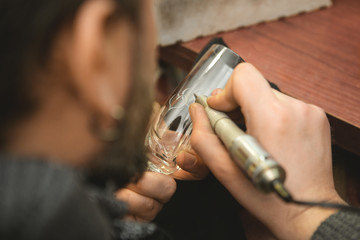 Bearded mature jeweler using engraving machine at his workshop