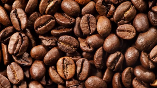 Close up of roasted brown coffee beans rotating. Top view