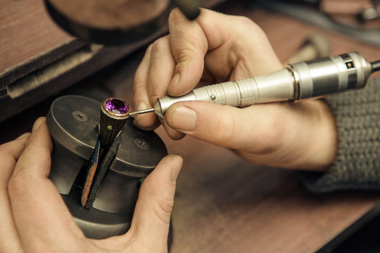 Close up of a jeweler repairing a ring with violet gemstone