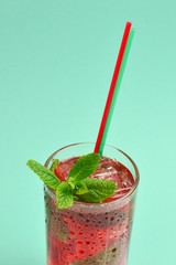 Red fresh drink with ice, grapefruit and mint on a green background. Space for text or design.