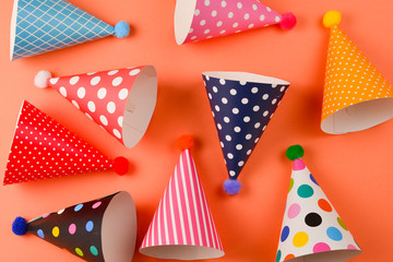 Obraz premium Colorful birthday caps on orange background. Top view.
