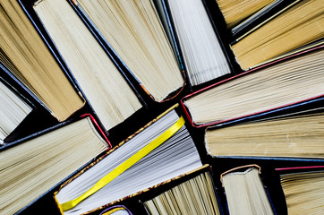 Naklejka premium Lots of colourful thick open books stand on a dark background