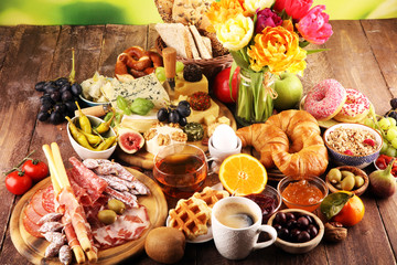 breakfast on table with bread buns, croissants, coffe and eggs