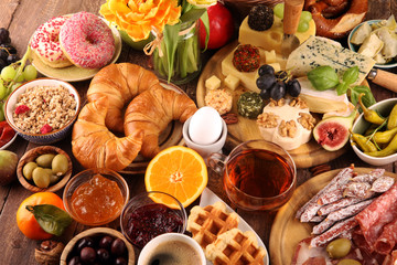 breakfast on table with bread buns, croissants, coffe and eggs